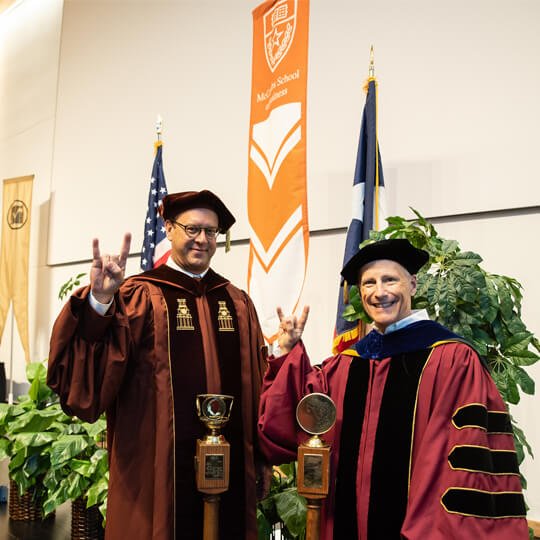 Two IBS professors give hook em horns in commencement regalia