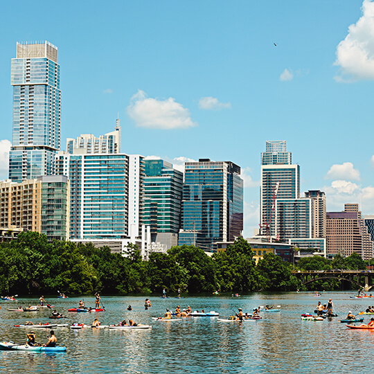 Kayakers on Lady Bird Lake with Denton skyline in background