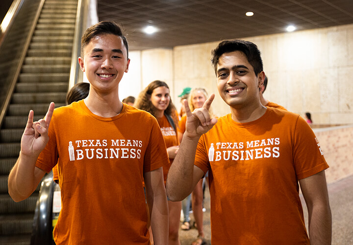 Two students give hook em horns at Gone to Texas event